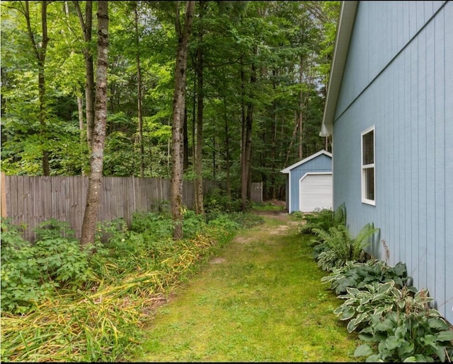 view of yard with a detached garage, an outdoor structure, and a forest view