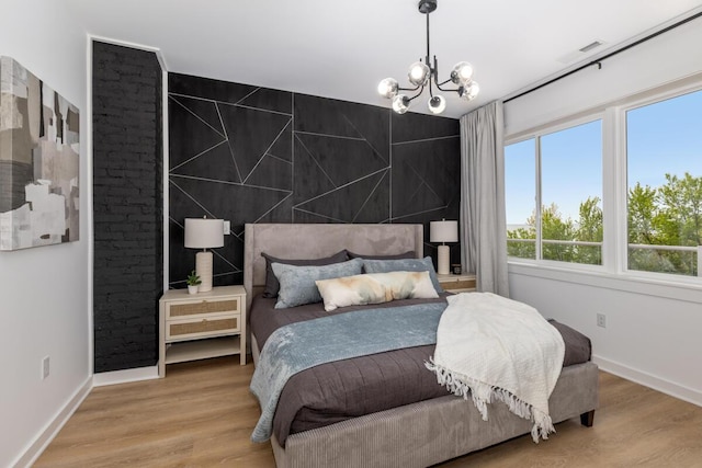 3500 Lakeshore Dr, Saint Joseph, MI 49085 - bedroom with a chandelier, an accent wall, light wood-type flooring, and baseboards