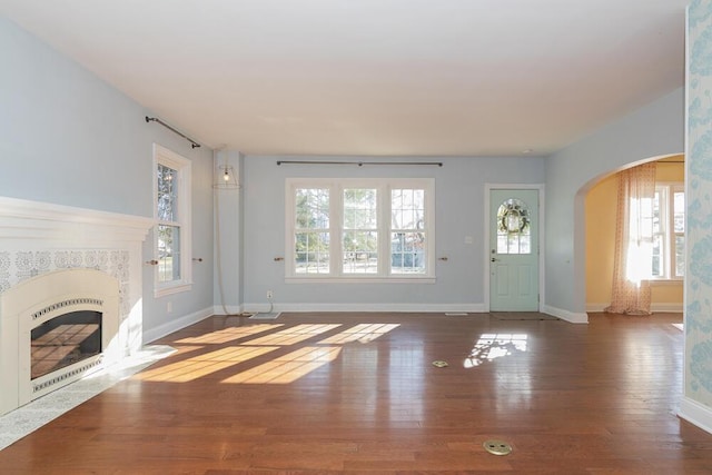 2106 Forest, Portage, MI 49002 - unfurnished living room with arched walkways, healthy amount of natural light, wood finished floors, and a fireplace