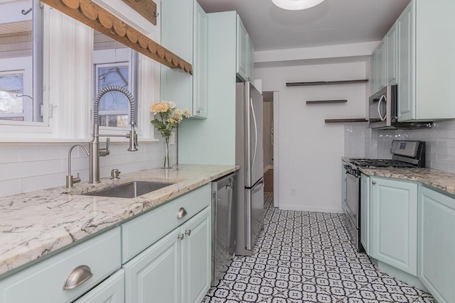 2106 Forest, Portage, MI 49002 - kitchen featuring appliances with stainless steel finishes, backsplash, a sink, light stone counters, and healthy amount of natural light