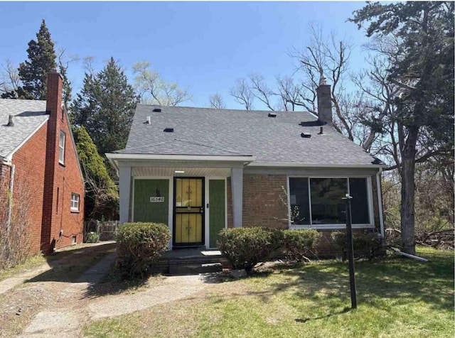 bungalow with a front lawn and roof with shingles