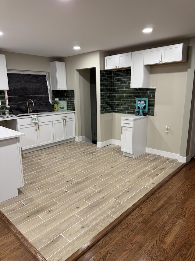 kitchen featuring decorative backsplash, light wood-style flooring, white cabinetry, recessed lighting, and a sink