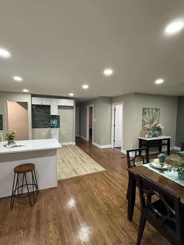 kitchen featuring white cabinetry, wood finished floors, recessed lighting, baseboards, and a breakfast bar