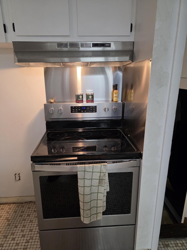 13851 Hillsdale Rd, Camden, MI 49232 - kitchen featuring stainless steel range with electric cooktop, under cabinet range hood, white cabinets, and tile patterned floors