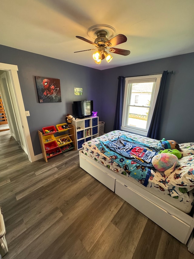 bedroom with dark wood-style flooring, a ceiling fan, and baseboards