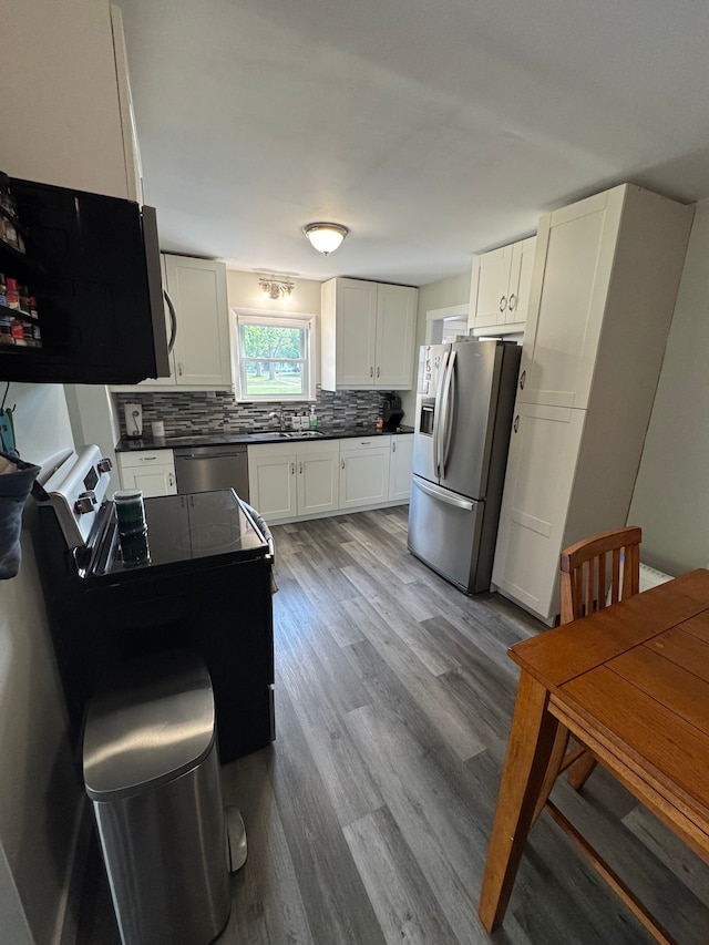 kitchen featuring appliances with stainless steel finishes, dark countertops, white cabinetry, and backsplash