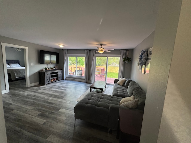 living area featuring a ceiling fan, dark wood finished floors, and baseboards