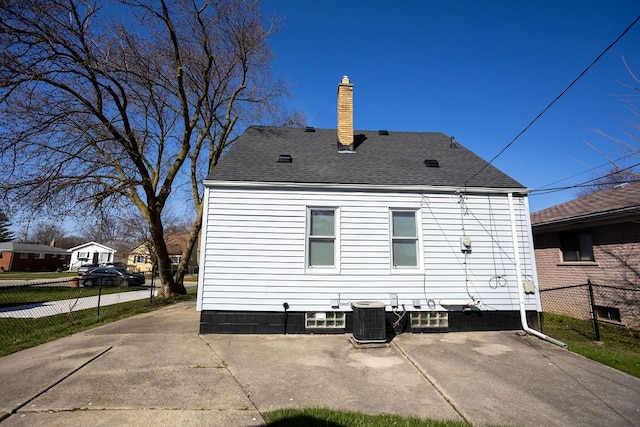 rear view of property with fence, a chimney, central AC, a shingled roof, and a patio area