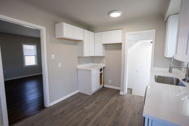 kitchen featuring a sink, dark wood finished floors, white cabinets, and light countertops