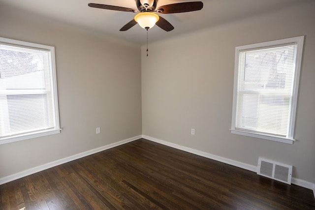 empty room featuring dark wood-type flooring, a ceiling fan, and baseboards