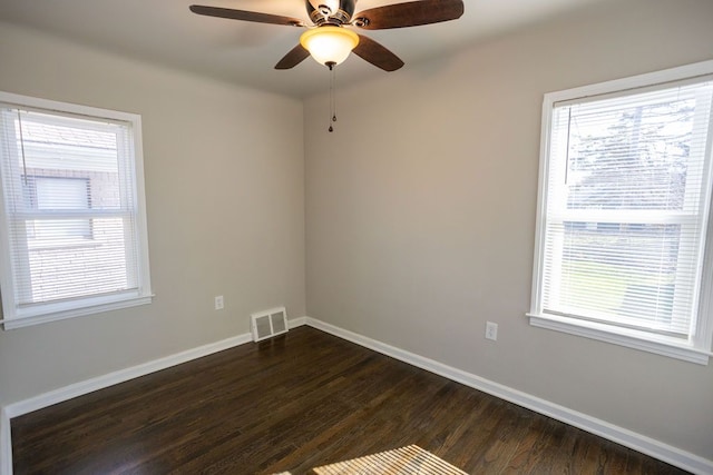unfurnished room with healthy amount of natural light, dark wood-type flooring, and baseboards