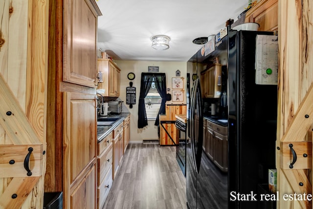 kitchen featuring light wood-style floors, freestanding refrigerator, baseboards, and a sink