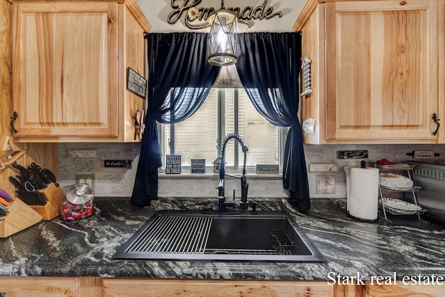 kitchen with light brown cabinetry, a sink, and backsplash