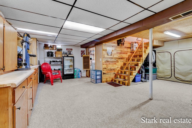 finished basement featuring stairway, carpet floors, and a paneled ceiling