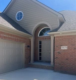 33806 Au Sable Dr, Chesterfield, MI 48047 - entrance to property featuring brick siding, roof with shingles, a garage, and driveway