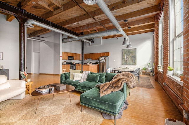 living room featuring brick wall, a towering ceiling, and light wood-style floors