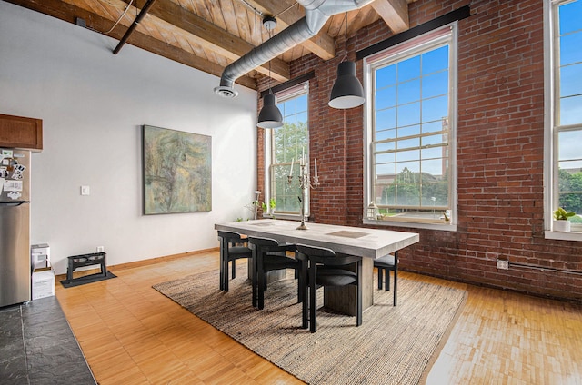 dining space featuring plenty of natural light, beam ceiling, wood ceiling, baseboards, and brick wall