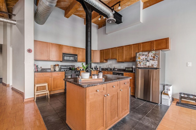 kitchen with black appliances, a high ceiling, a sink, a center island, and dark stone countertops