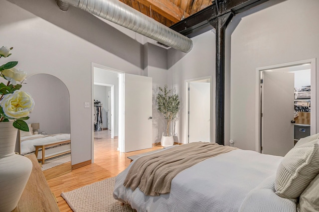 bedroom featuring a high ceiling, arched walkways, and light wood finished floors