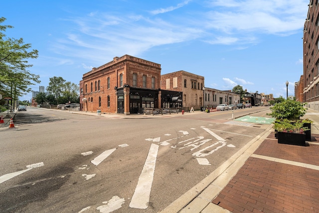 view of asphalt road with sidewalks, curbs, and street lighting