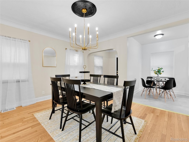 17524 Woodingham Dr, Detroit, MI 48221 - dining area with arched walkways, light wood-style floors, crown molding, a chandelier, and baseboards