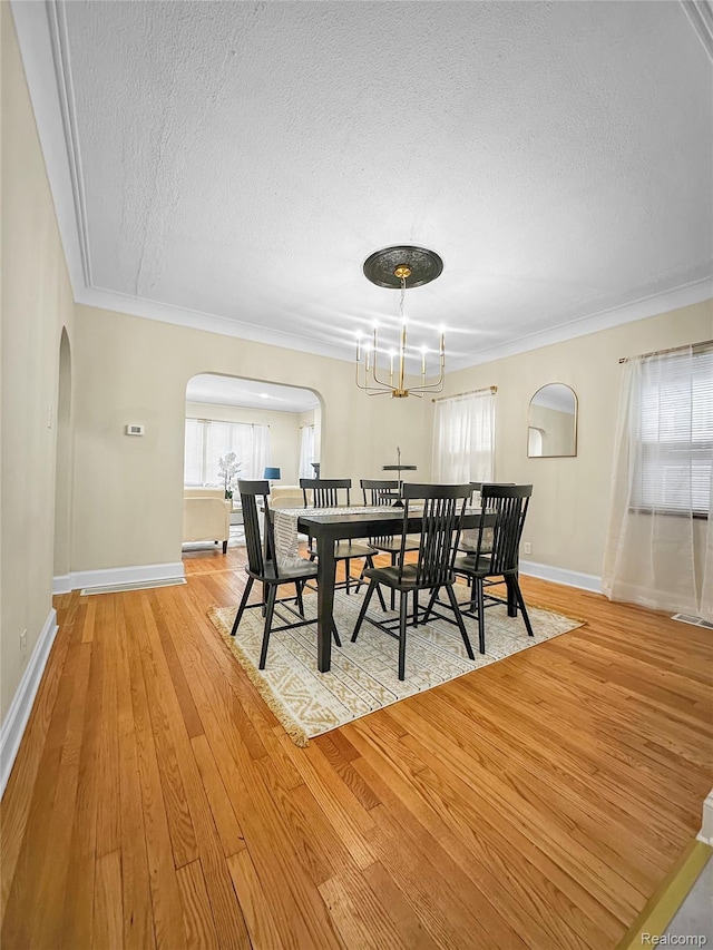 17524 Woodingham Dr, Detroit, MI 48221 - dining area with arched walkways, a textured ceiling, ornamental molding, light wood-type flooring, and baseboards
