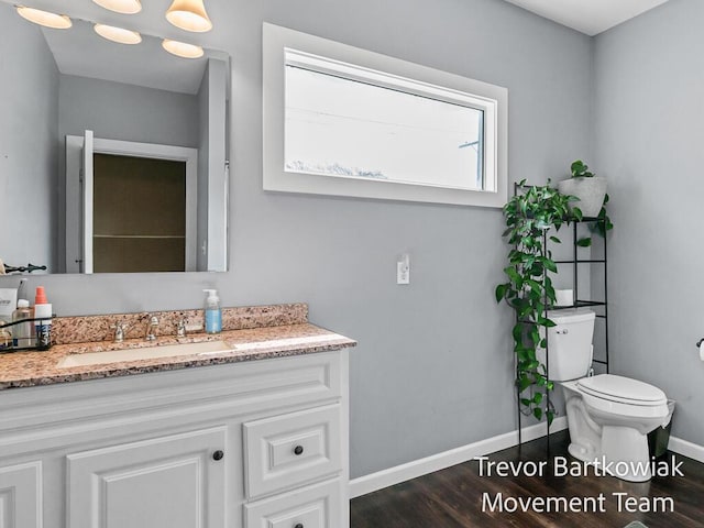 2200 Morton Ave, Muskegon, MI 49441 - bathroom featuring wood finished floors, baseboards, toilet, and vanity