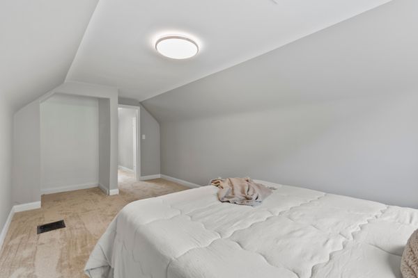 bedroom featuring light carpet, vaulted ceiling, and baseboards