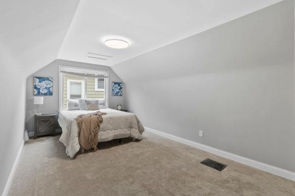 carpeted bedroom featuring lofted ceiling and baseboards