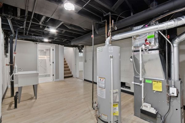 finished basement with gas water heater, stairway, wood finished floors, and heating unit