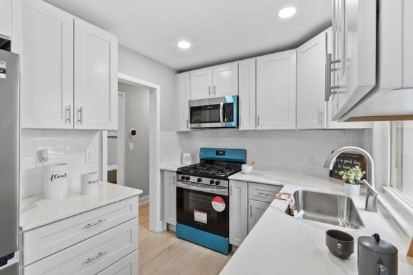 kitchen with stainless steel appliances, a sink, backsplash, white cabinetry, and recessed lighting