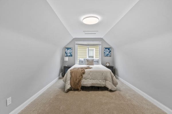 carpeted bedroom featuring vaulted ceiling and baseboards