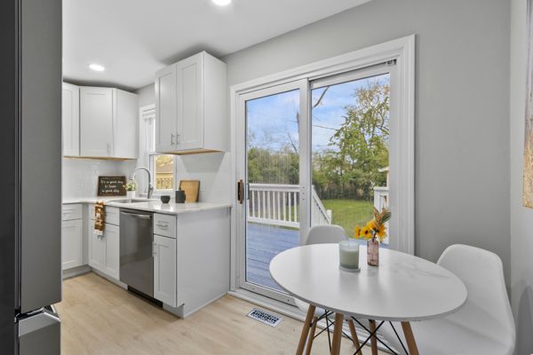 kitchen with dishwasher, a sink, light wood-type flooring, light countertops, and white cabinetry