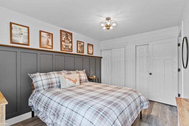 14043 Landings Way, Fenton, MI 48430 - bedroom featuring wood finished floors, a decorative wall, wainscoting, and multiple closets