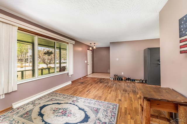 unfurnished living room featuring wood finished floors, baseboard heating, and baseboards