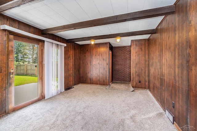spare room with beamed ceiling, wood walls, and carpet flooring