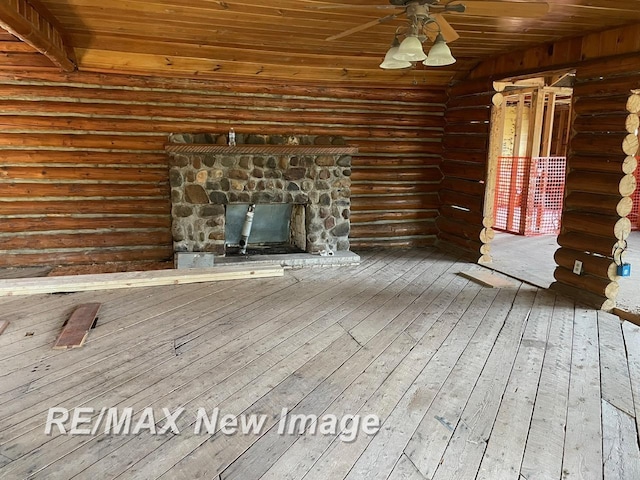 724 W Tobacco Ridge Trl, Beaverton, MI 48612 - unfurnished living room featuring wood ceiling, ceiling fan, log walls, hardwood / wood-style floors, and a stone fireplace