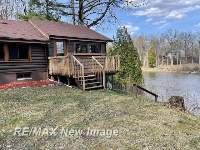 724 W Tobacco Ridge Trl, Beaverton, MI 48612 - back of house featuring a shingled roof, a deck with water view, and a yard