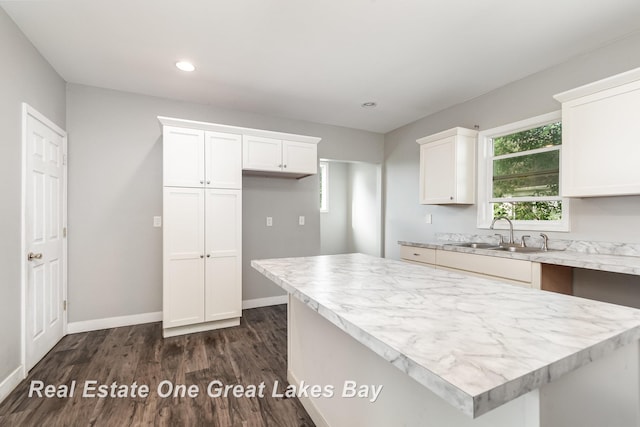 1006 Cass Ave, Bay City, MI 48708 - kitchen featuring a sink, dark wood-style flooring, white cabinets, light countertops, and baseboards