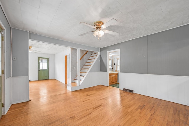 237 Main St, Walkerville, MI 49459 - empty room featuring a ceiling fan, light wood-style floors, stairway, and a wainscoted wall