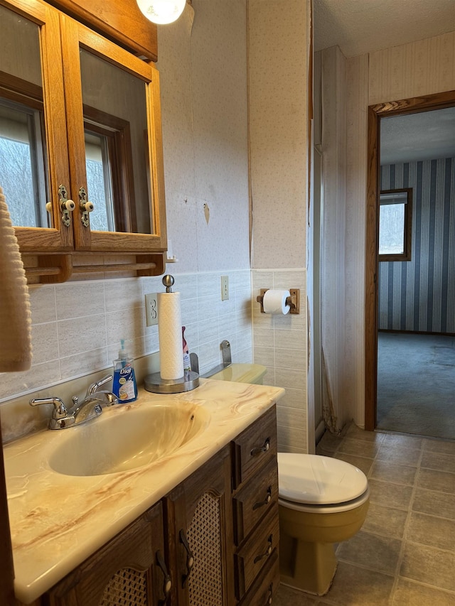 3135 Montgomery Rd, Bellaire, MI 49615 - half bathroom with wallpapered walls, toilet, vanity, and wainscoting