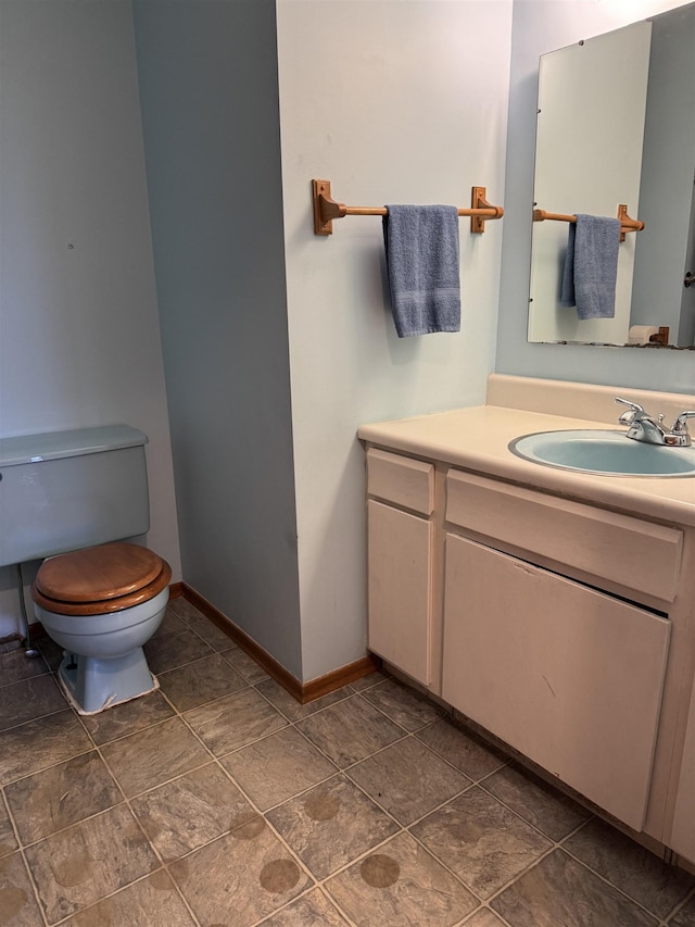 3135 Montgomery Rd, Bellaire, MI 49615 - bathroom featuring toilet, baseboards, vanity, and stone finish flooring