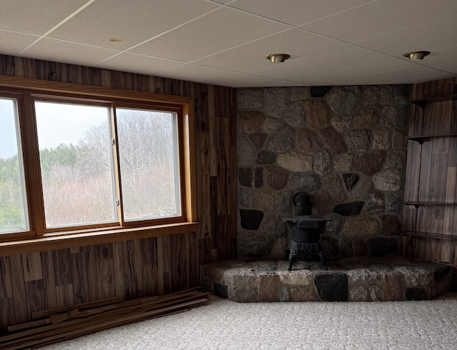 3135 Montgomery Rd, Bellaire, MI 49615 - carpeted living area with a paneled ceiling, wooden walls, and a wood stove