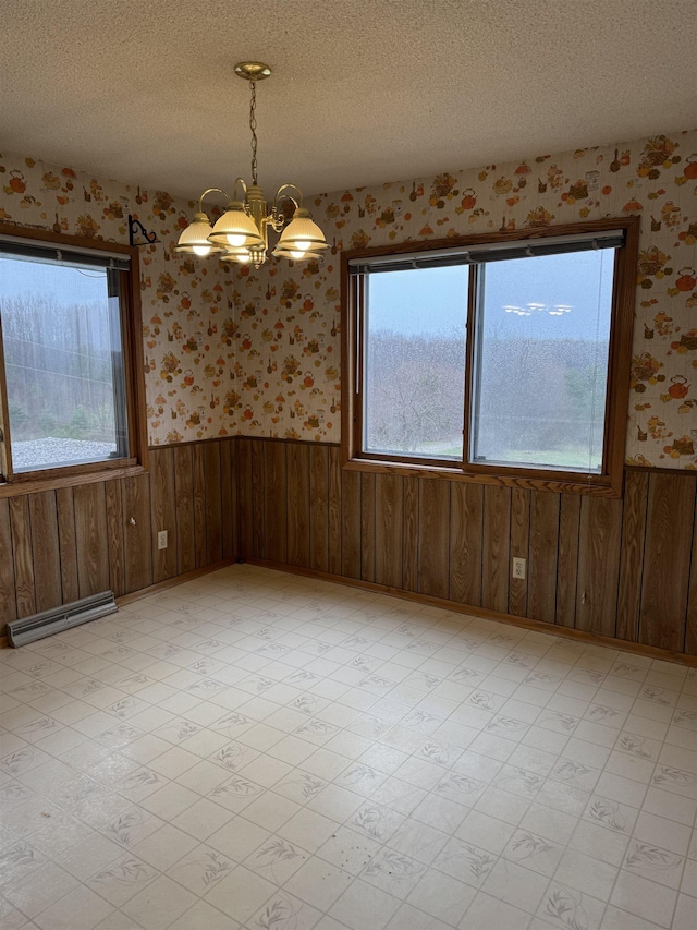 3135 Montgomery Rd, Bellaire, MI 49615 - spare room featuring a baseboard heating unit, wainscoting, wallpapered walls, healthy amount of natural light, and a chandelier