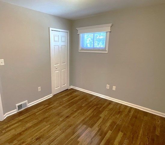 unfurnished room featuring baseboards and dark wood-style flooring