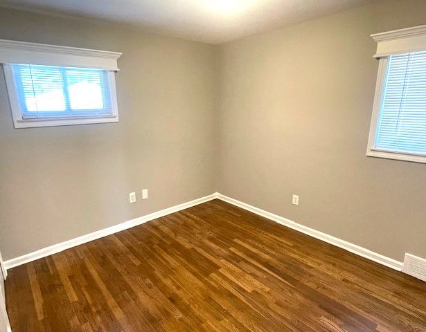 empty room featuring baseboards and dark wood finished floors