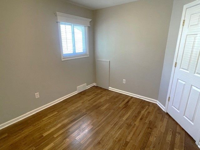 empty room with dark wood-style floors and baseboards