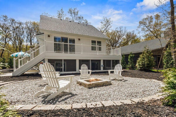 4108 Chippewa Trl, New Buffalo, MI 49117 - rear view of property featuring a fire pit, a balcony, stairway, and a sunroom