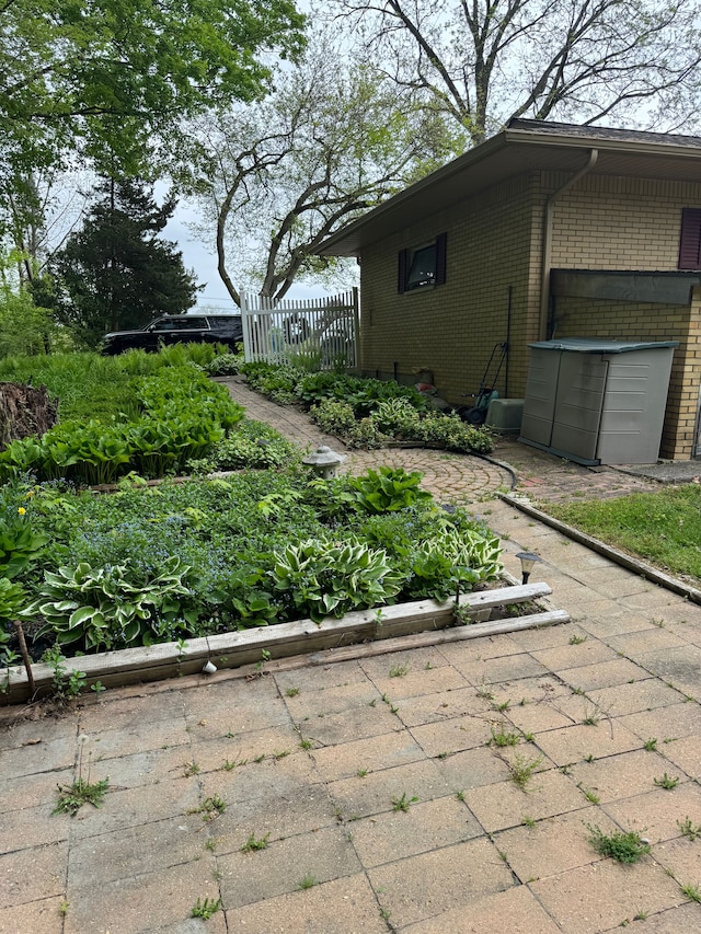 2071 N Belsay Rd, Burton, MI 48509 - view of property exterior with brick siding, fence, and a garden