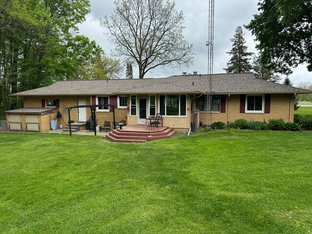 2071 N Belsay Rd, Burton, MI 48509 - rear view of house featuring brick siding, a lawn, a wooden deck, an outdoor structure, and a storage unit